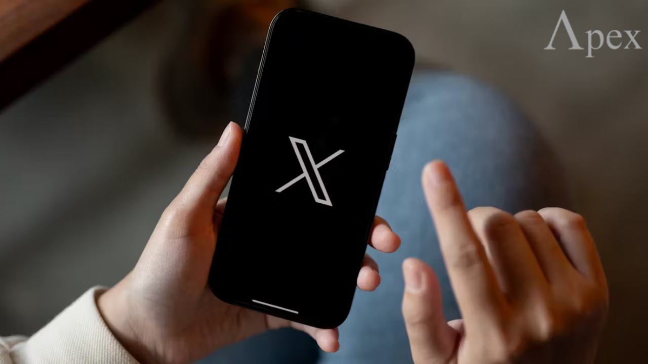 Person holding a smartphone showing the X logo.