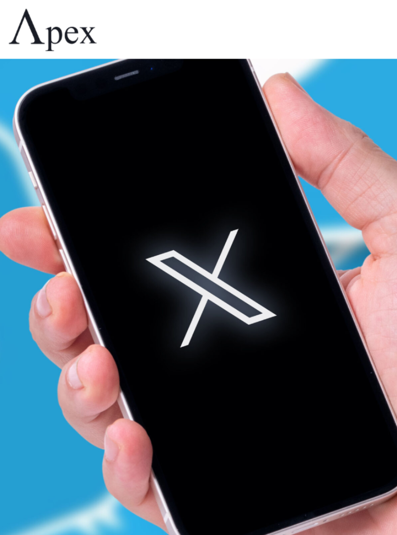 X App on Smartphone Hand holding a smartphone displaying the X logo on a black screen