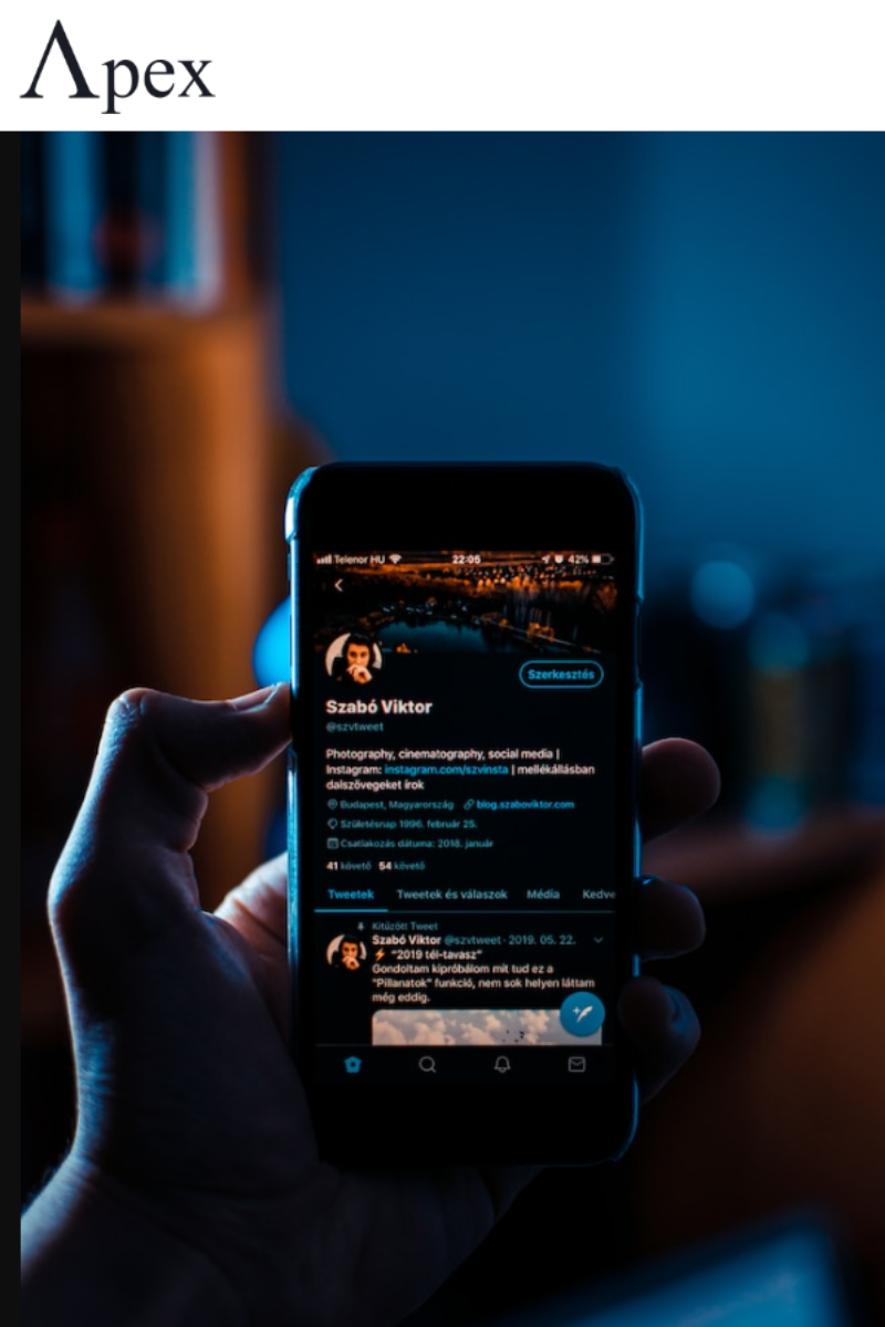 X Profile in Dark Mode Hand holding a smartphone displaying a Twitter profile in dark mode at night