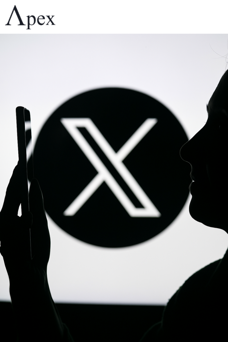X Logo and User Silhouette Silhouette of a person holding a smartphone in front of a large X logo background